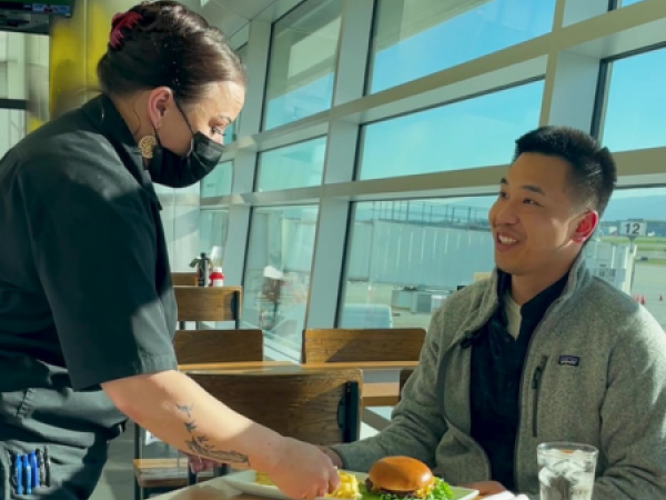 John eats a cheeseburger from Gordon Biersch.